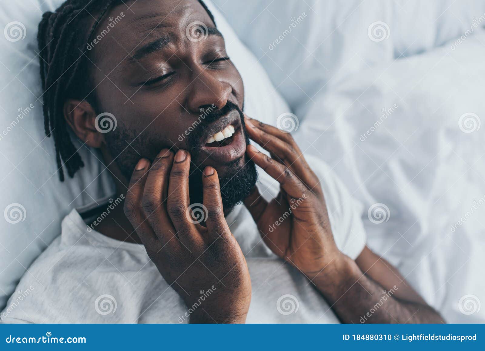 african american man suffering from jaw pain in bedroom