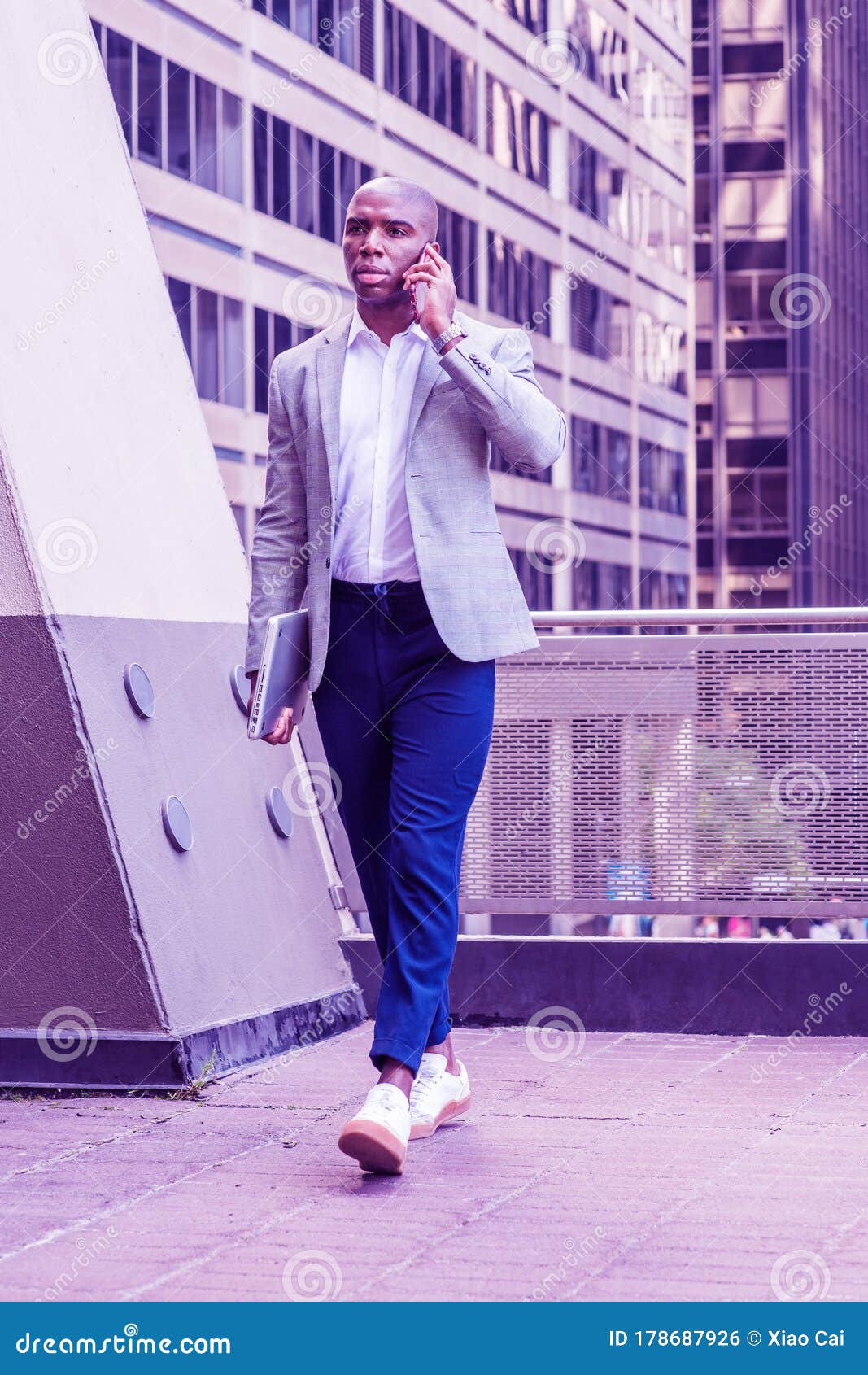 young african american man traveling working new york city wearing gray blazer blue pants white sneakers carrying laptop 178687926
