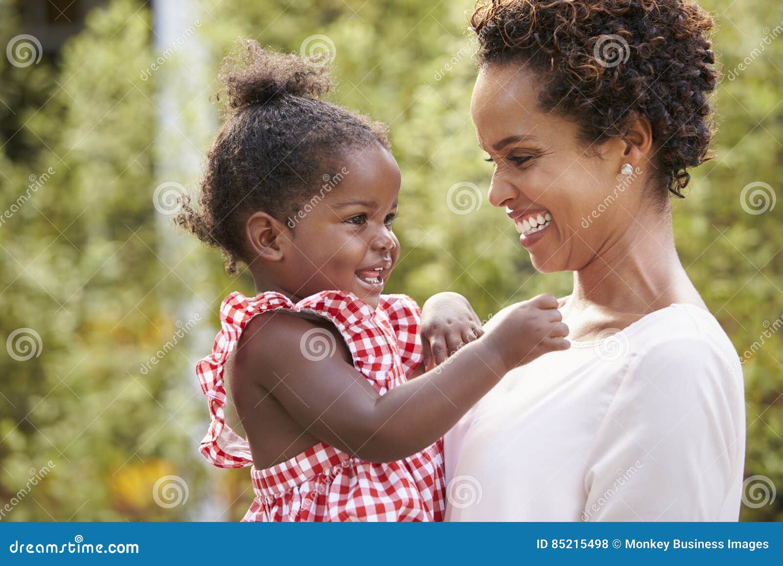 young african american mother holds baby daughter in garden