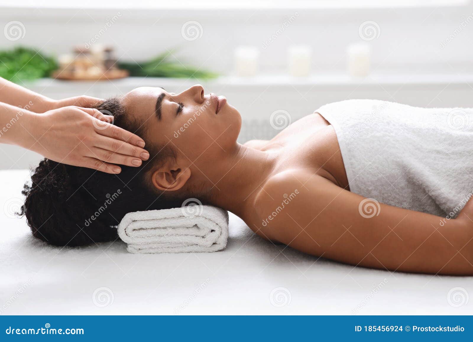 African American Woman Getting Head Massage From Therapist At Spa Stock