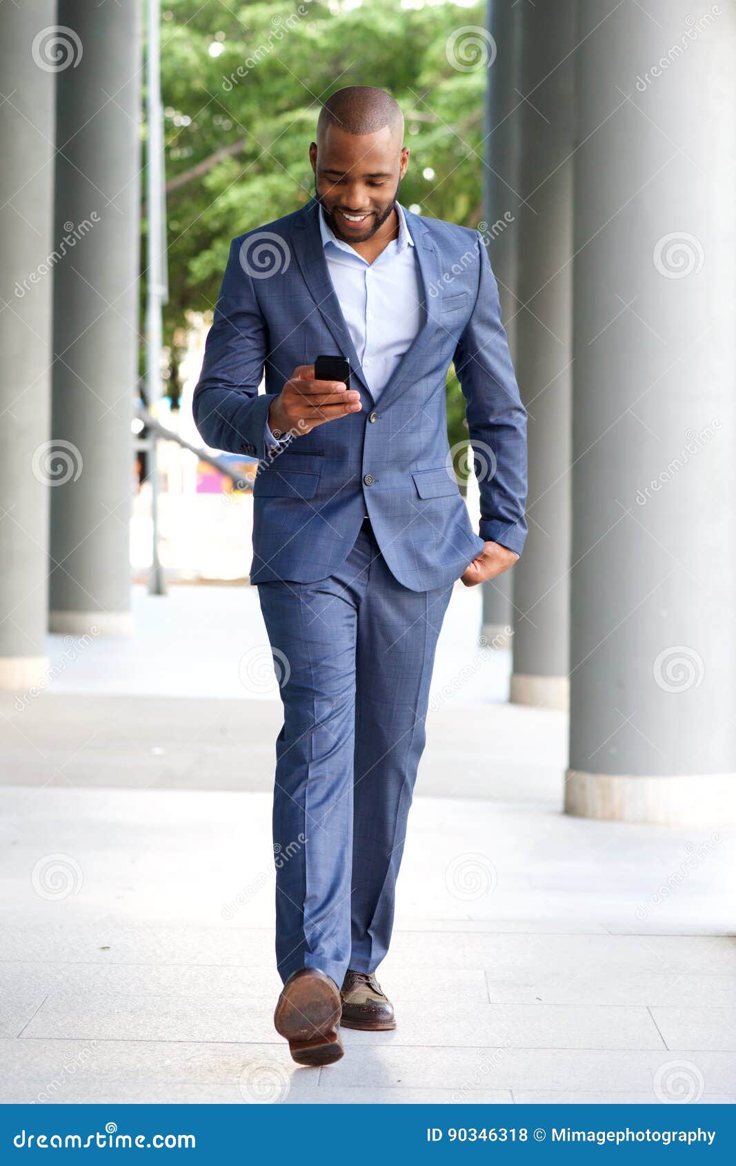 Young African Businessman Walking Looking at Cell Phone Stock Photo ...