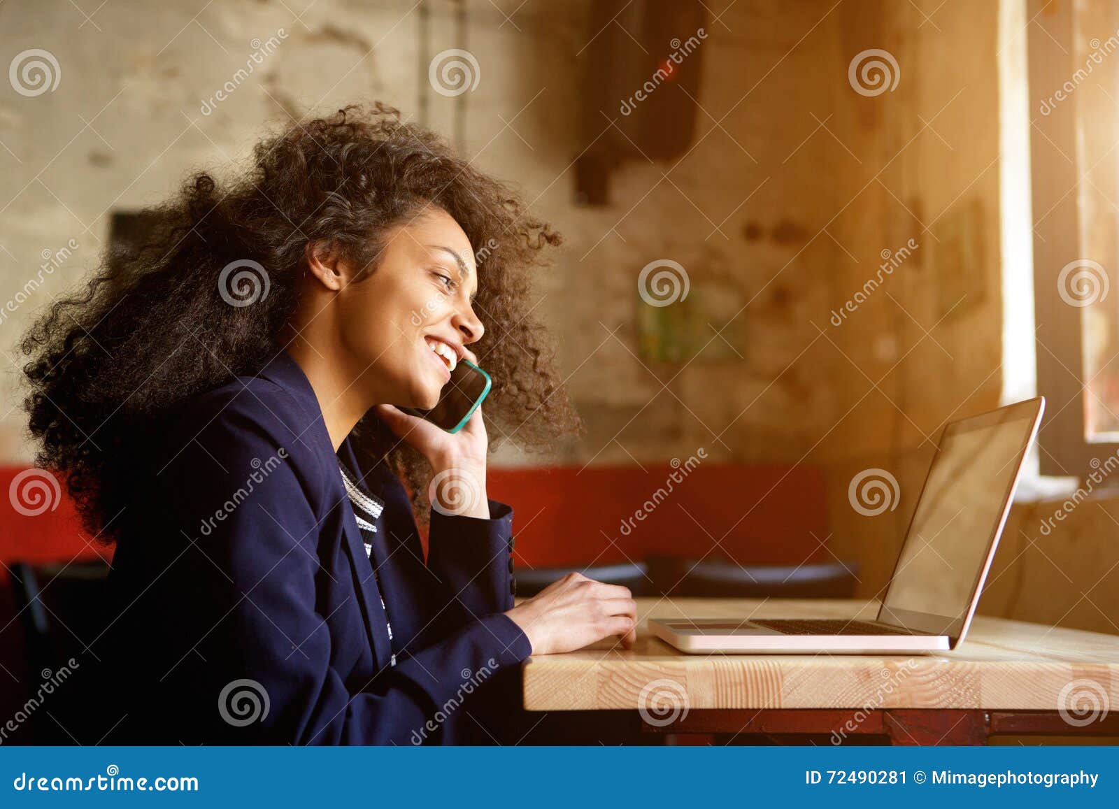 young african woman relaxing in cafe and making phone call
