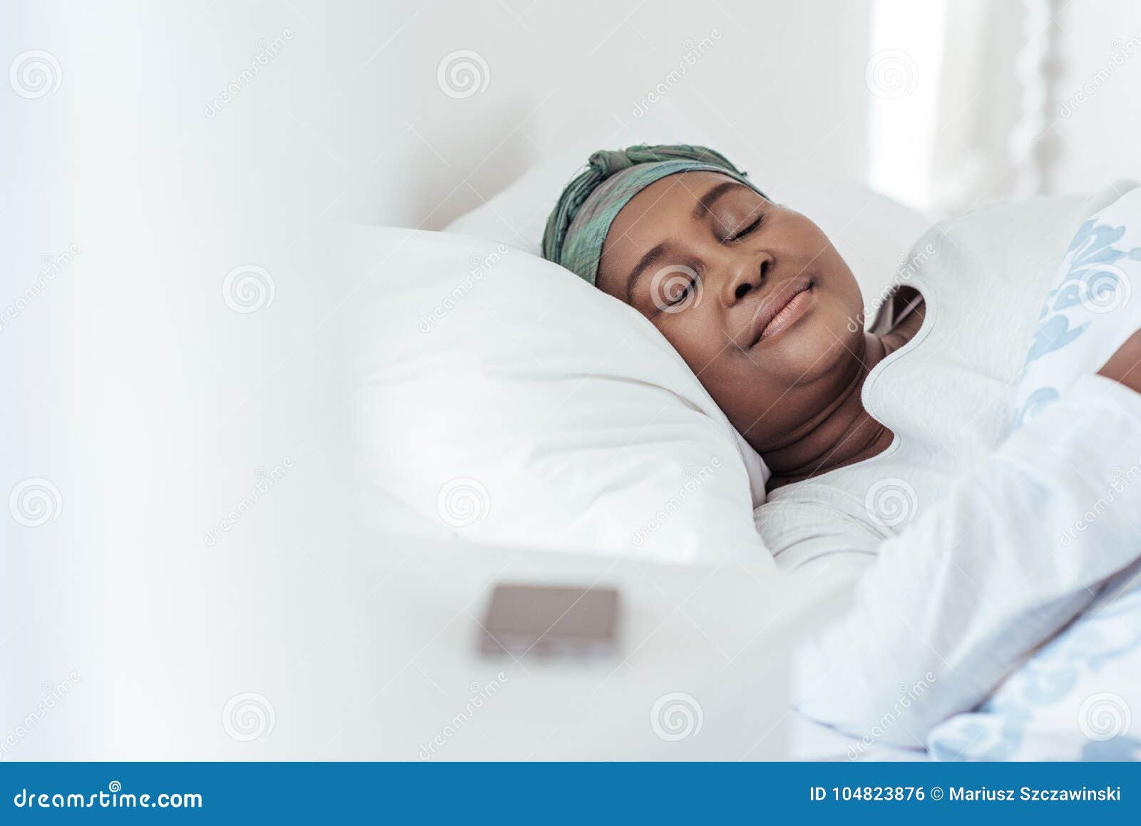 young african woman wearing a headscarf sleeping in bed