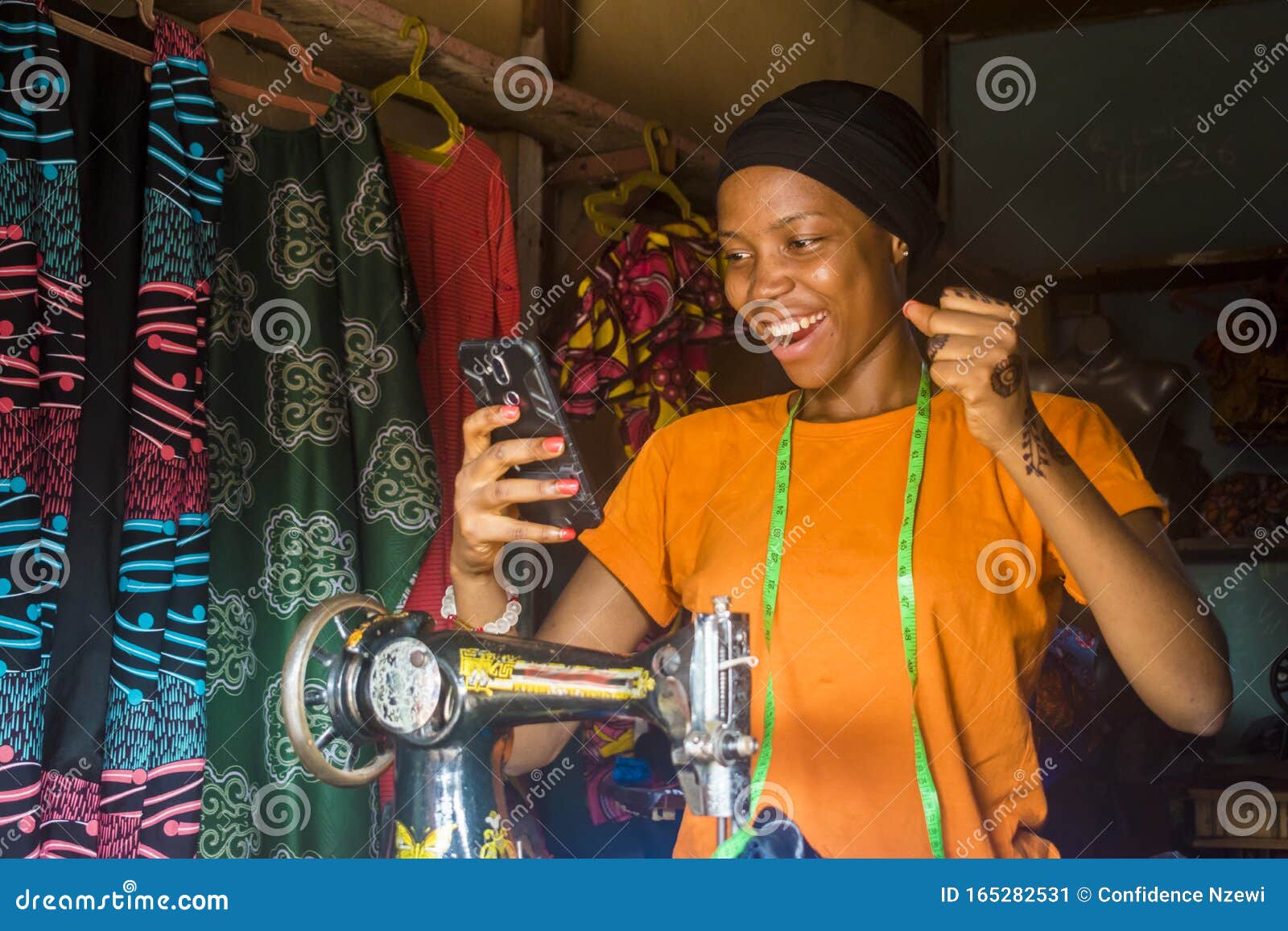african woman who is a tailor feeling excited and happy and jubilant while viewing content on her mobile phone