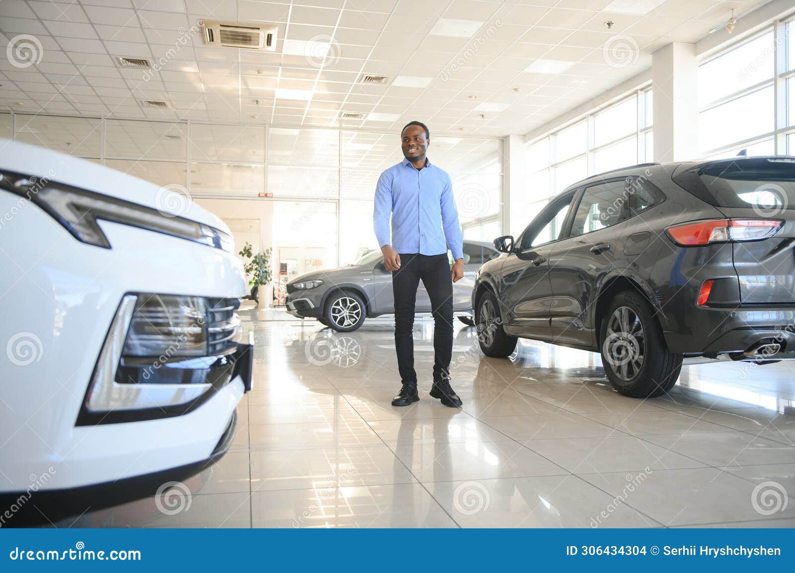 young africanamerican man came to see automobiles in dealership or cars showroom