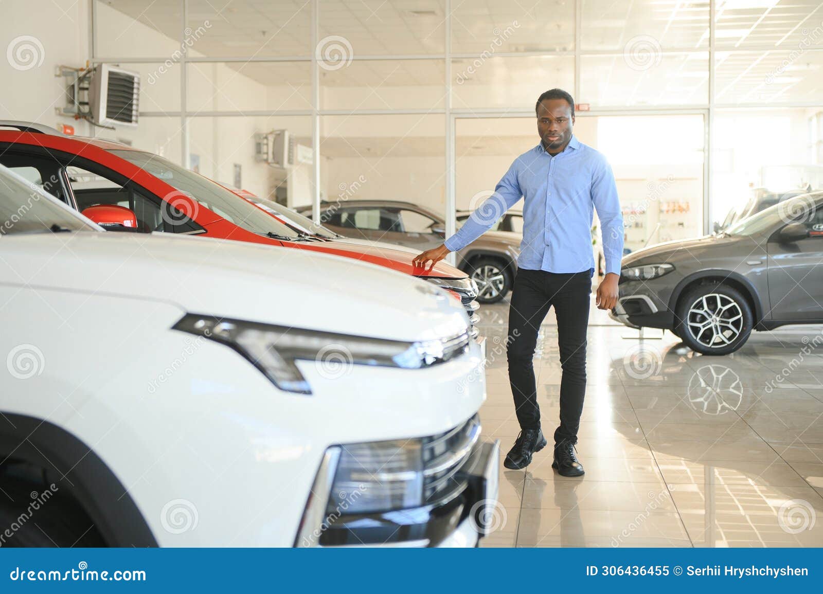 young africanamerican man came to see automobiles in dealership or cars showroom