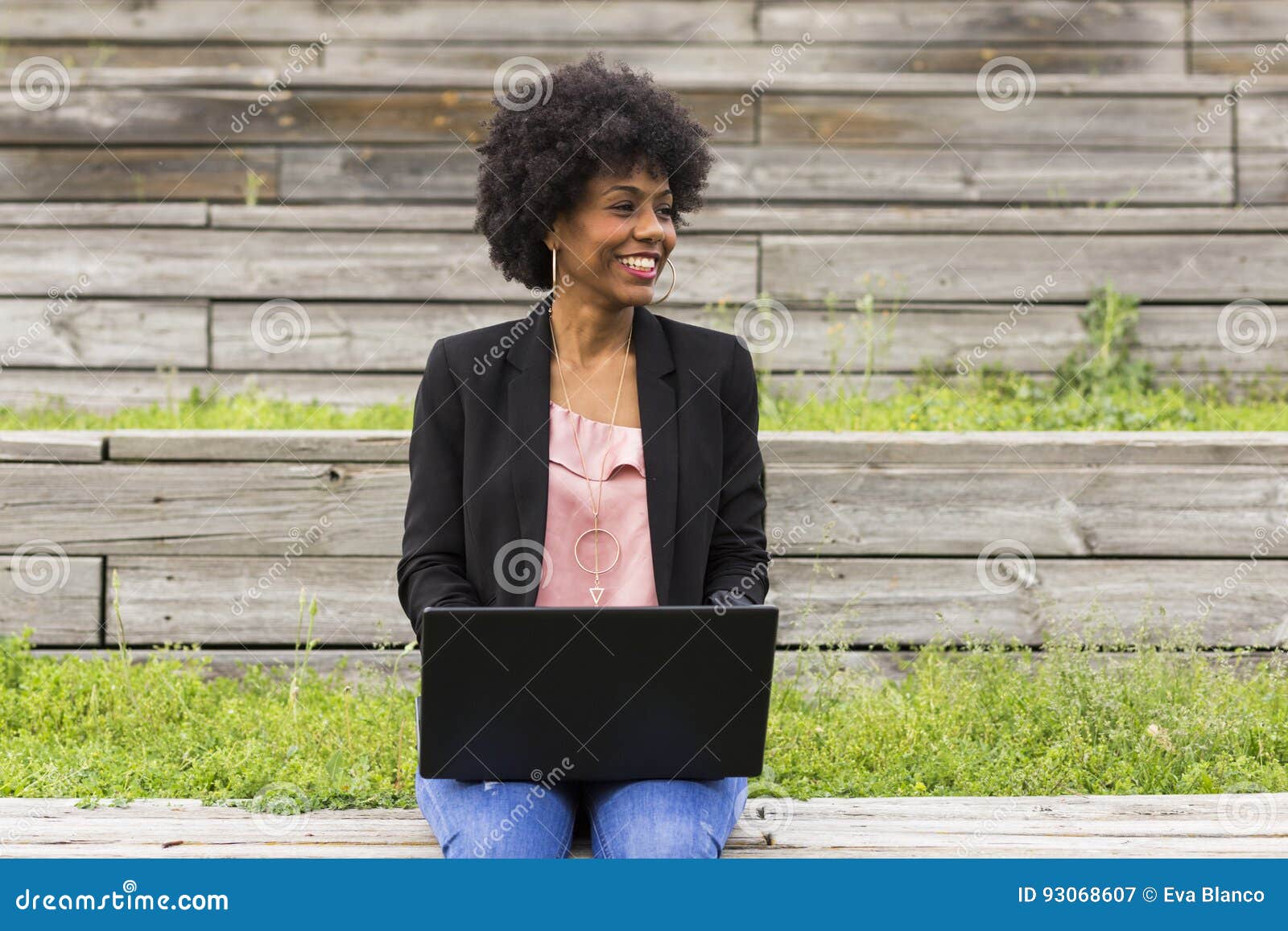 young afro american woman using laptop. green backgrounds. casual clothing. lifestyles. business.millennial.