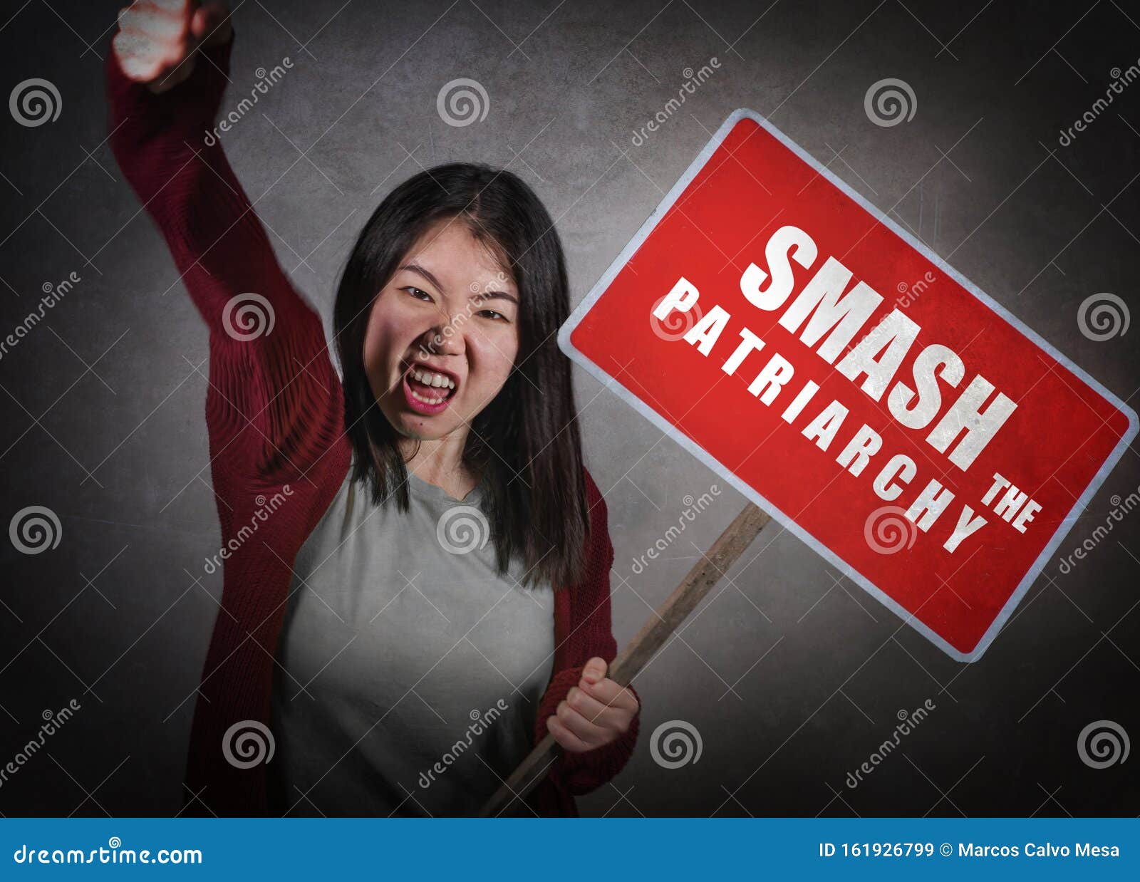 young aggressive ultra feminist asian korean woman holding protest billboard with smash the patriarchy text standing for women