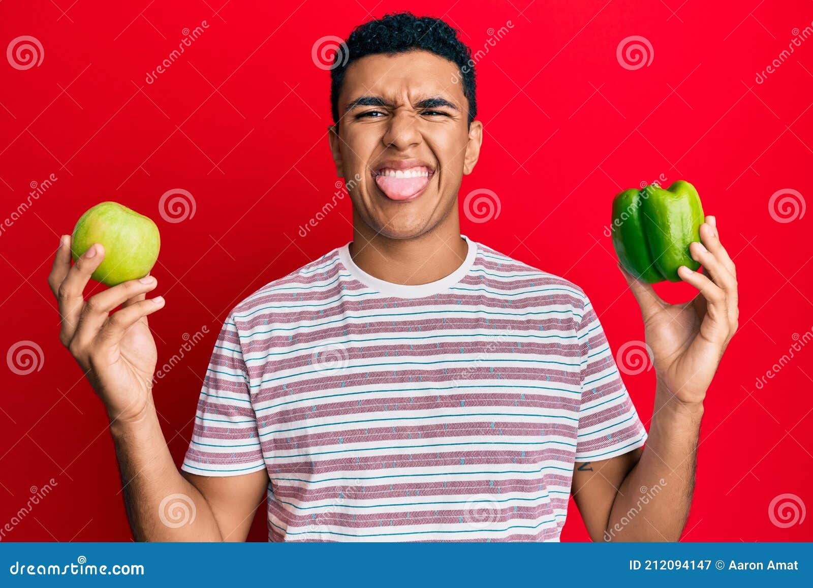 Young Arab Man Holding Green Apple and Pepper Sticking Tongue Out Happy ...