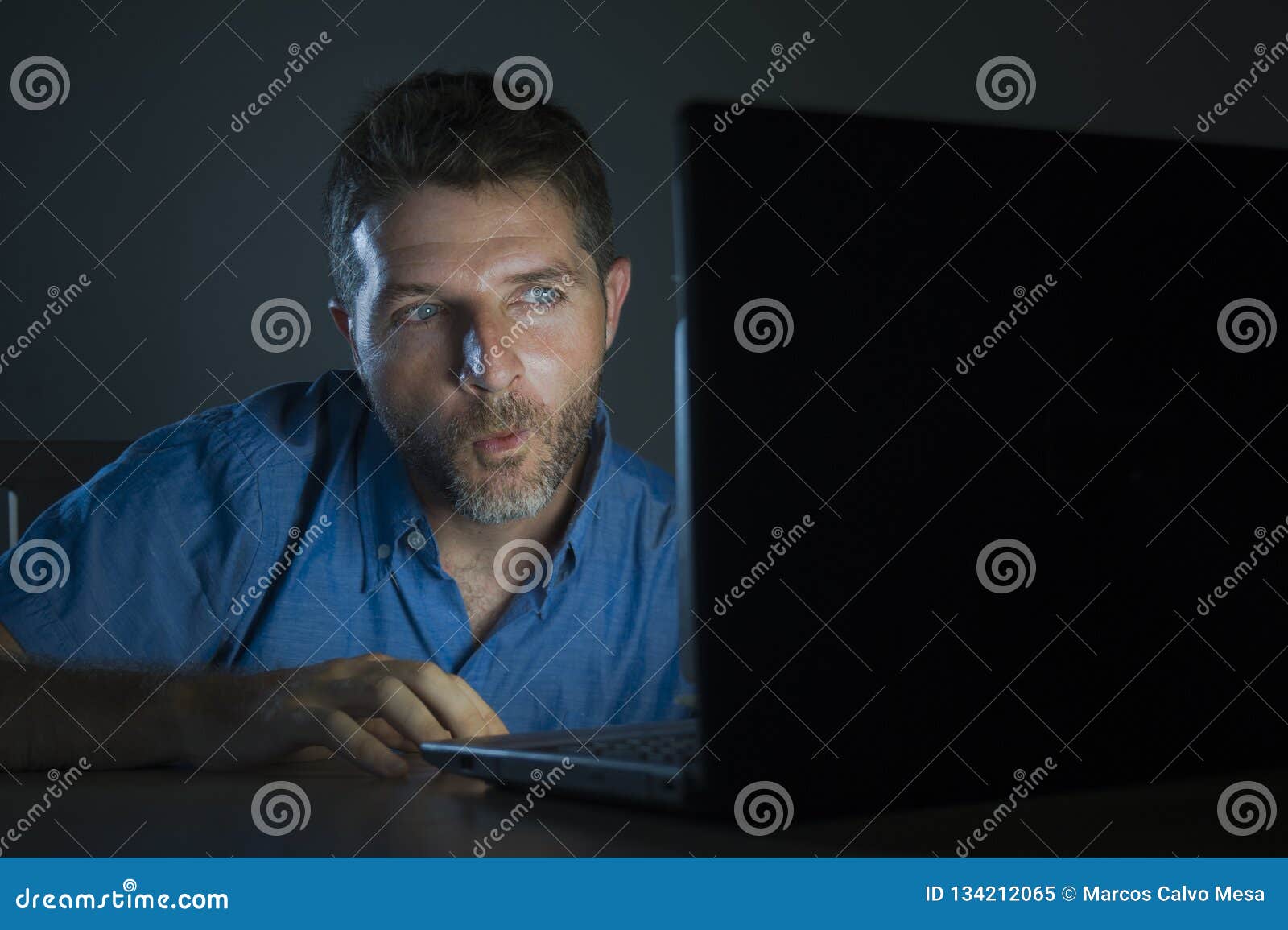 Young Aroused and Excited Sex Addict Man Watching Mobile Online in Laptop Computer Light Night at Home in Stock Image