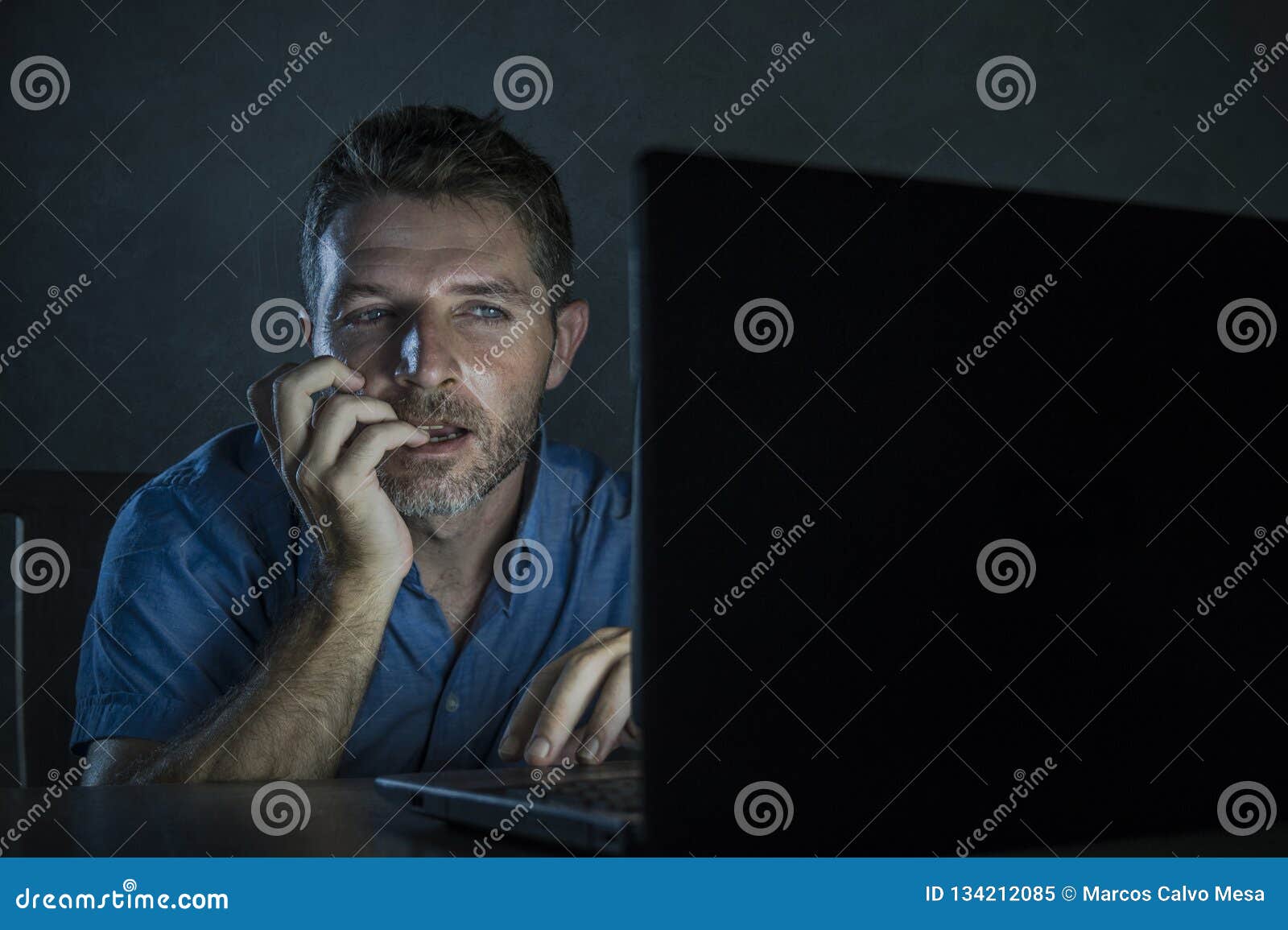Young Aroused and Excited Sex Addict Man Watching Mobile Online in Laptop Computer Light Night at Home in Stock Image picture