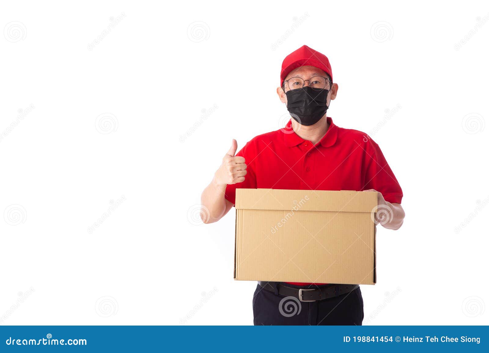 young asian delivery man in red uniform with  face mask, carrry cardboard box in hands  on white background