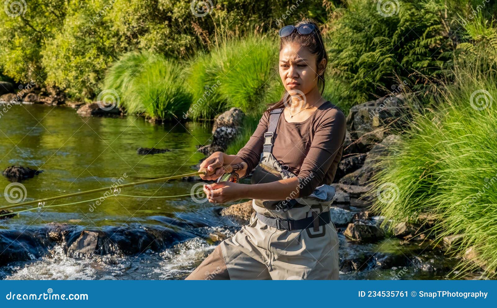 An asian female fly fisher women wearing waders and resting a rod on her  shoulder, as she looks where to fish on a river in Scotland Stock Photo -  Alamy