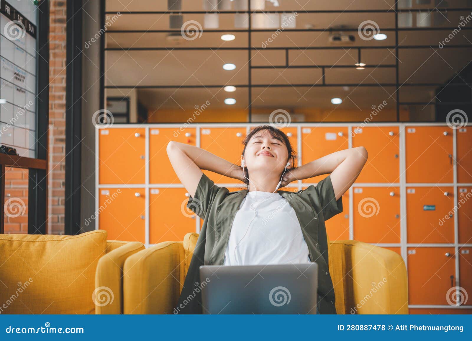 young asian freelancers are stretching oneself and relaxing after working and planning to work while working on laptop in the cafe