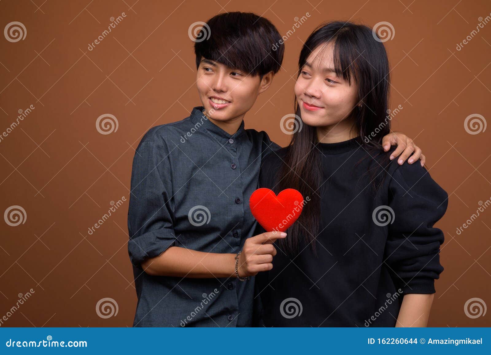 Young Asian Lesbian Couple Together And In Love Against Brown Ba Stock