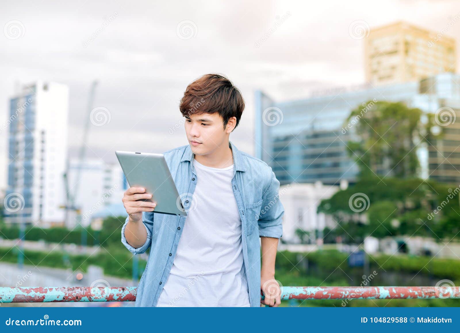 young asian man tourist using digita; tablet outdoor in the city
