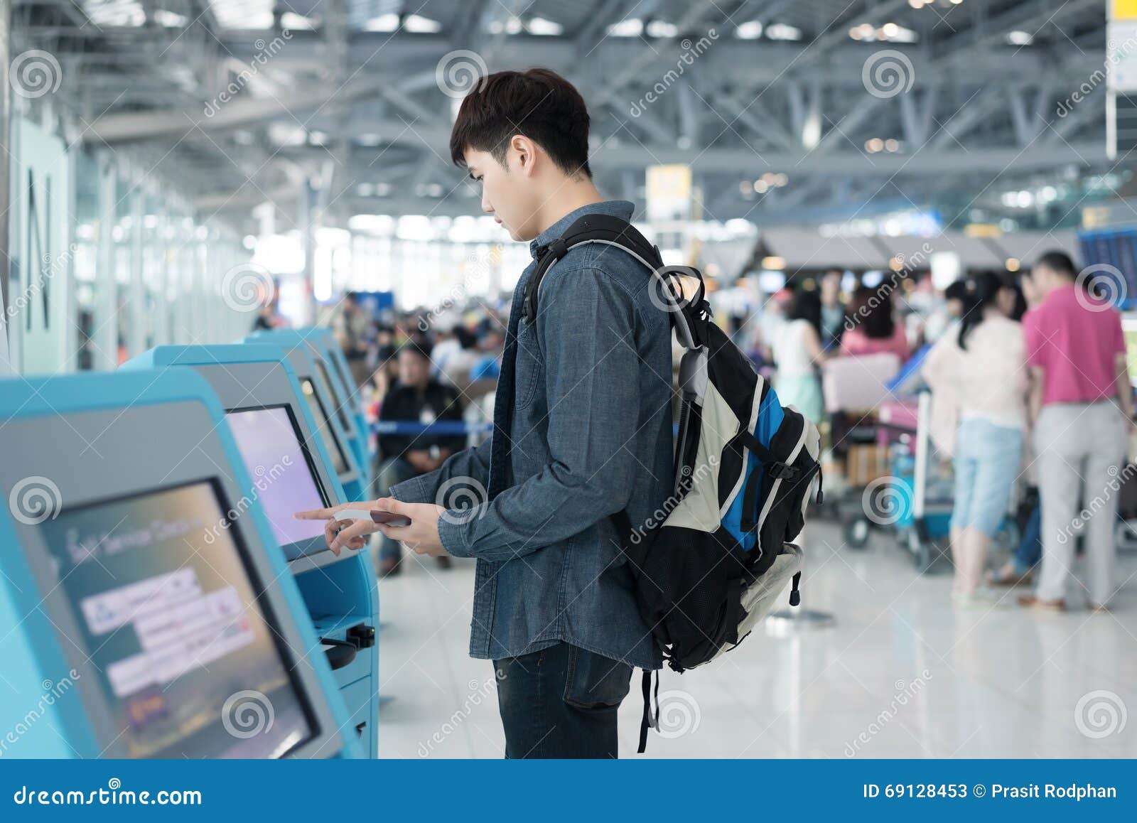 young asian man using self check-in kiosks in airport