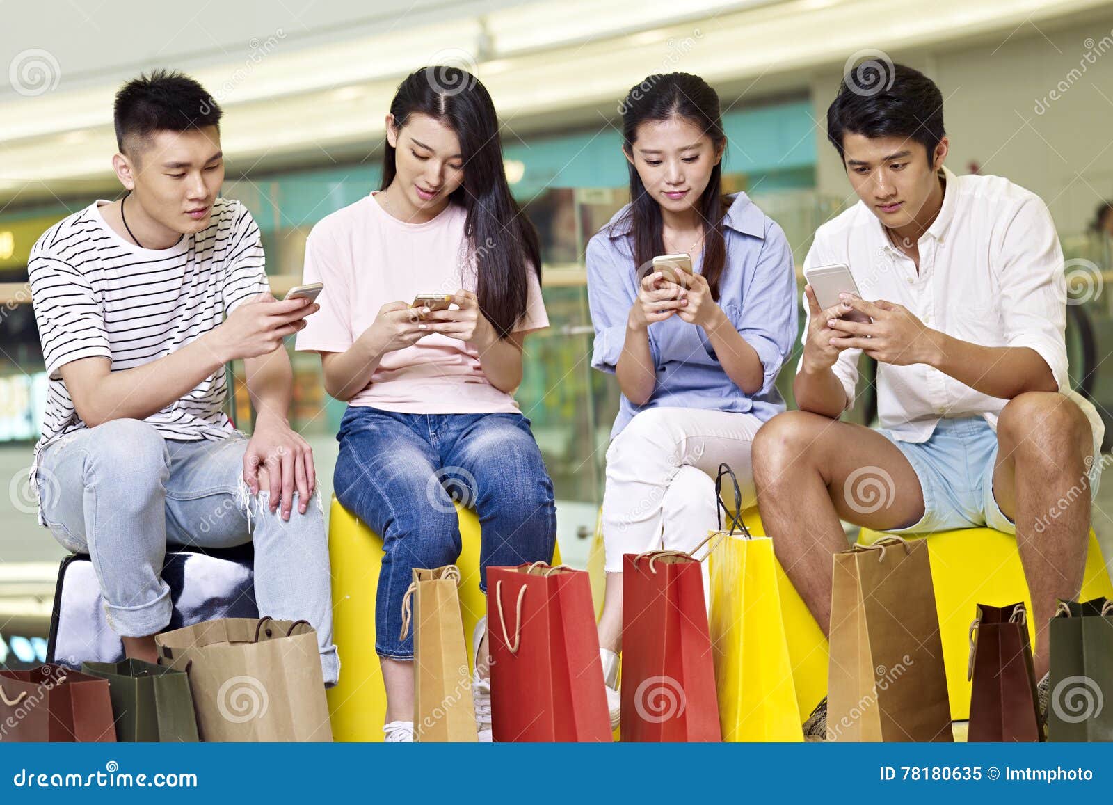 Group Of Young Asian People Sitting And Addicted To Playing Mobile