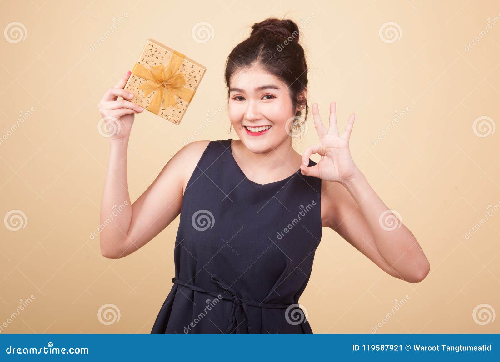 Young Asian Woman Show OK with a Gift Box. Stock Image - Image of beige