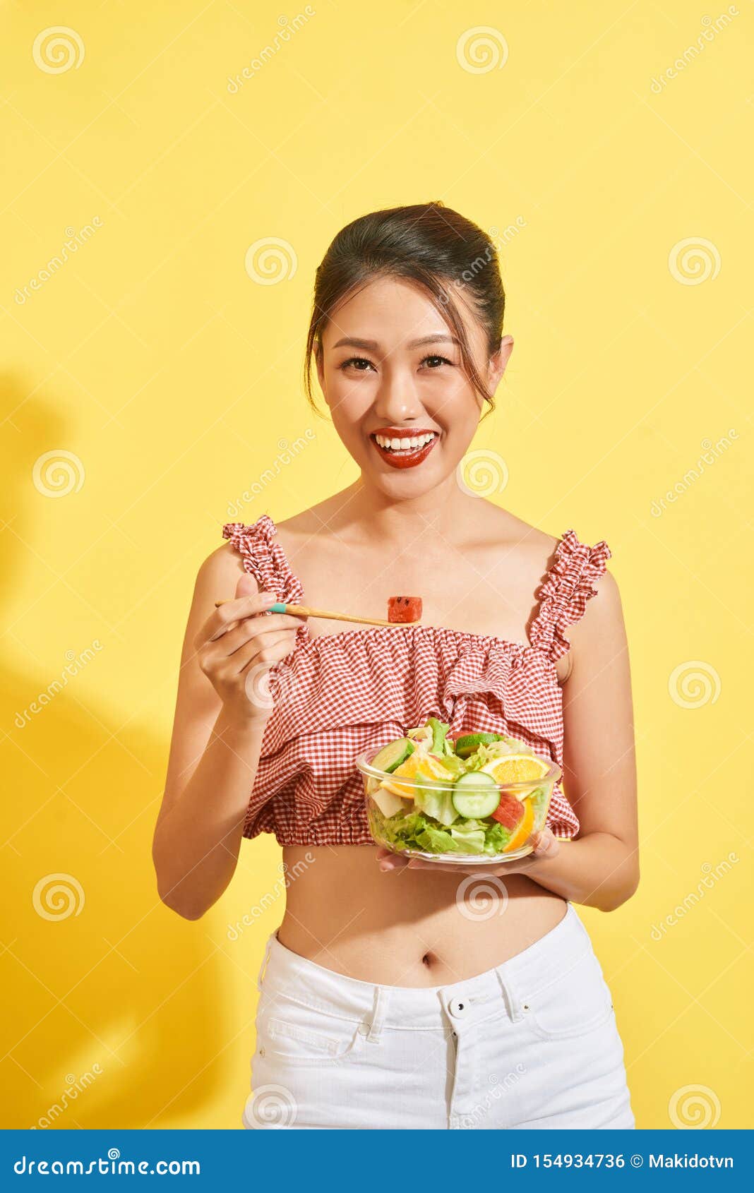 Young Asian Woman Smiling And Holding Vegetable And Salad On Yellow