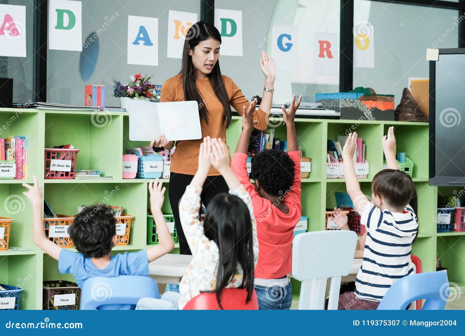 young asian woman teacher teaching kids in kindergarten classroom, preschool education concept