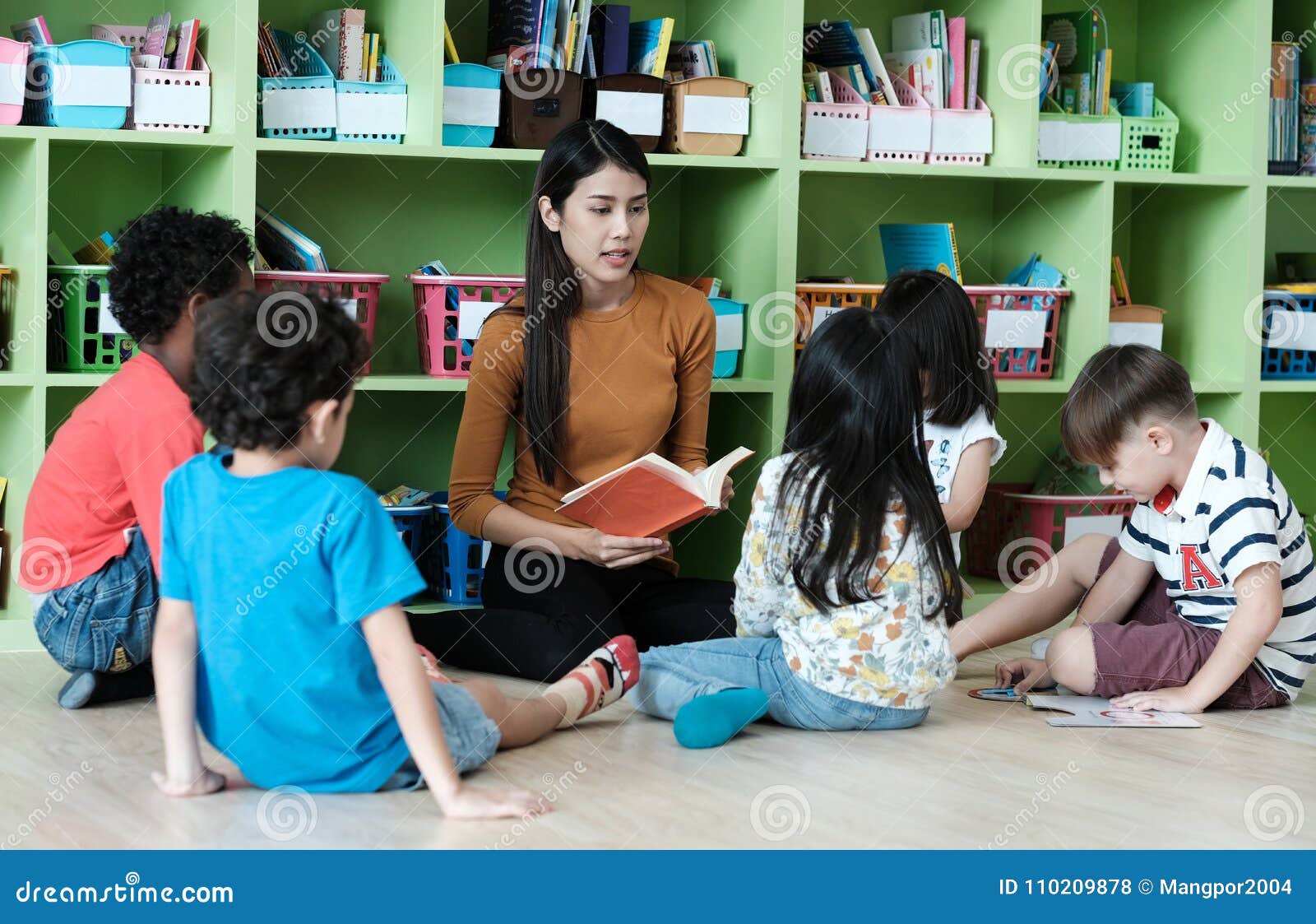 young asian woman teacher teaching kids in kindergarten classroom, preschool education concept