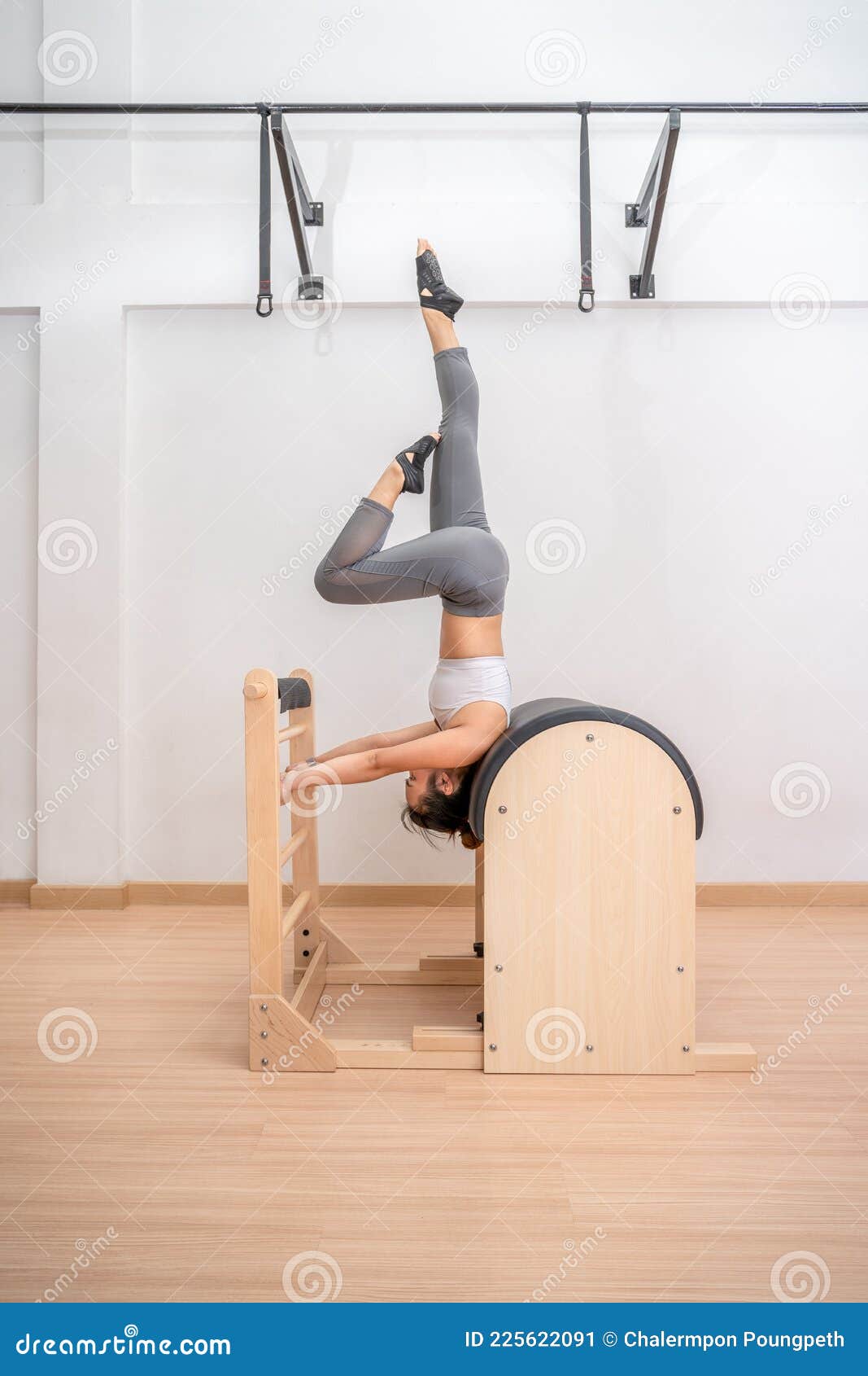 Young Asian Woman Working on Pilates Ladder Barrel Machine during