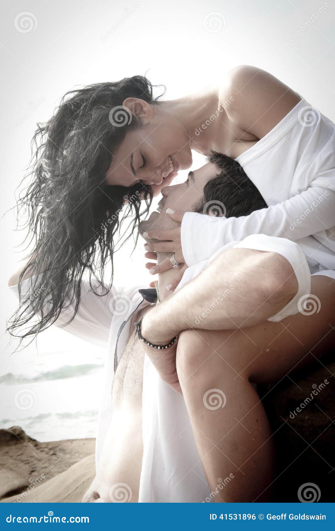 young attractive couple flirting outdoors on beach rocks