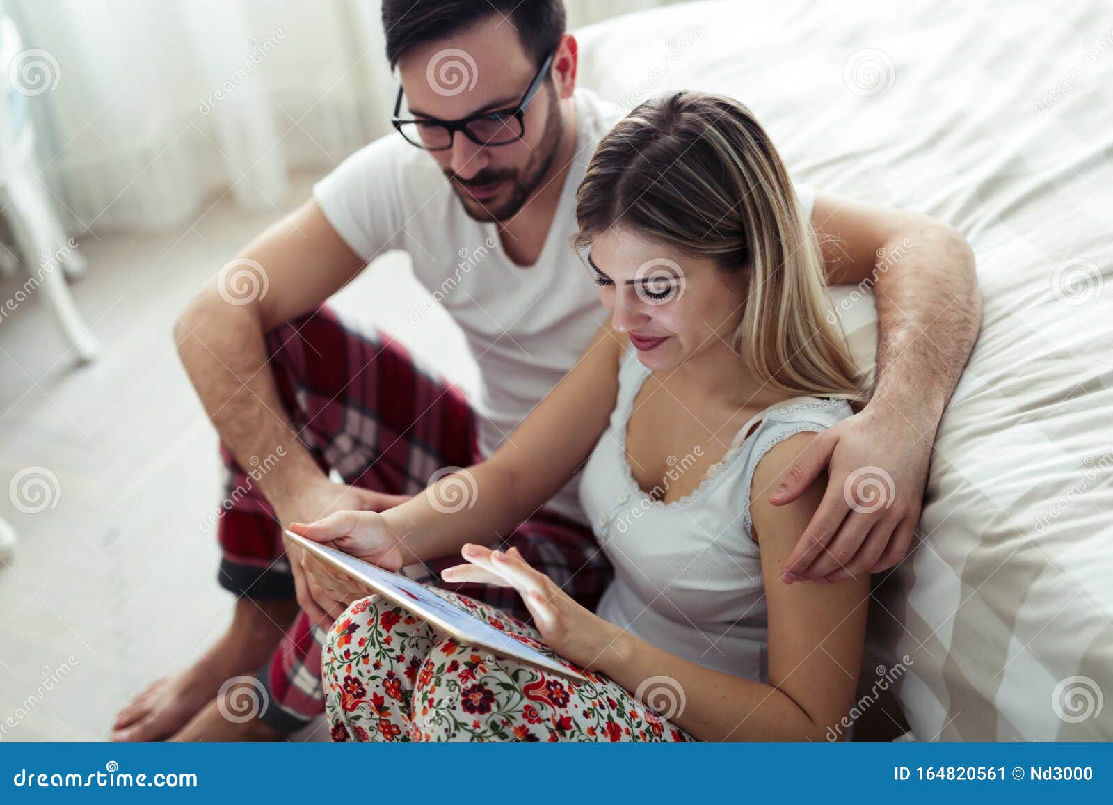 Young Attractive Couple Using Digital Tablet In Bedr