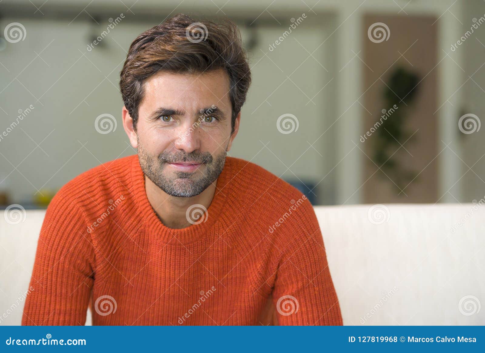 young attractive and happy 30s man smiling relaxed and comfortable sitting at living room sofa couch in his modern apartment cheer
