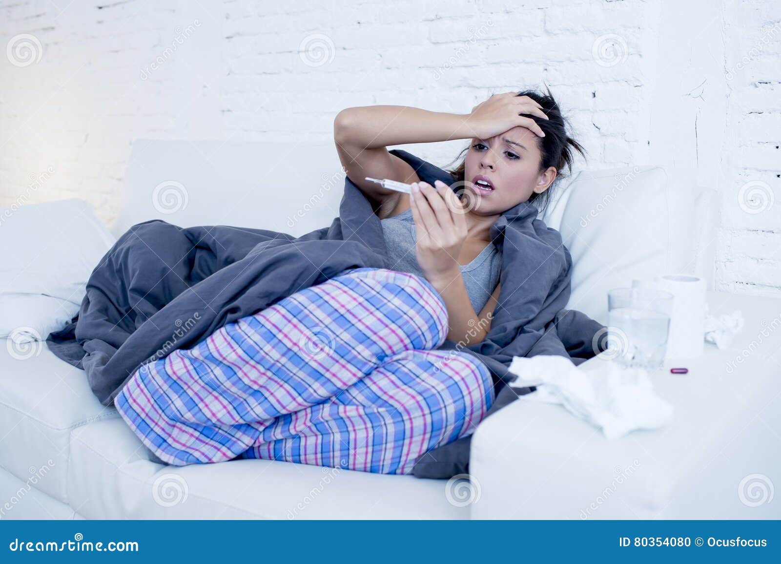 young attractive hispanic woman lying sick at home couch in cold and flu in gripe disease symptom