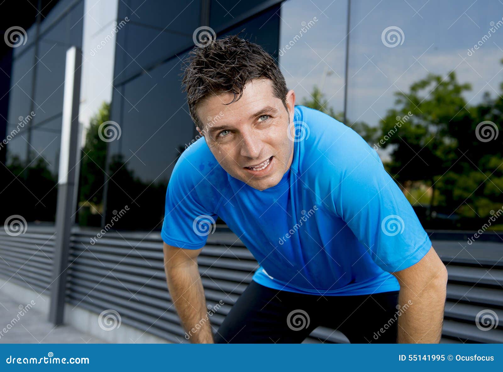 young attractive man leaning exhausted after running session sweating taking a break to recover in urban street