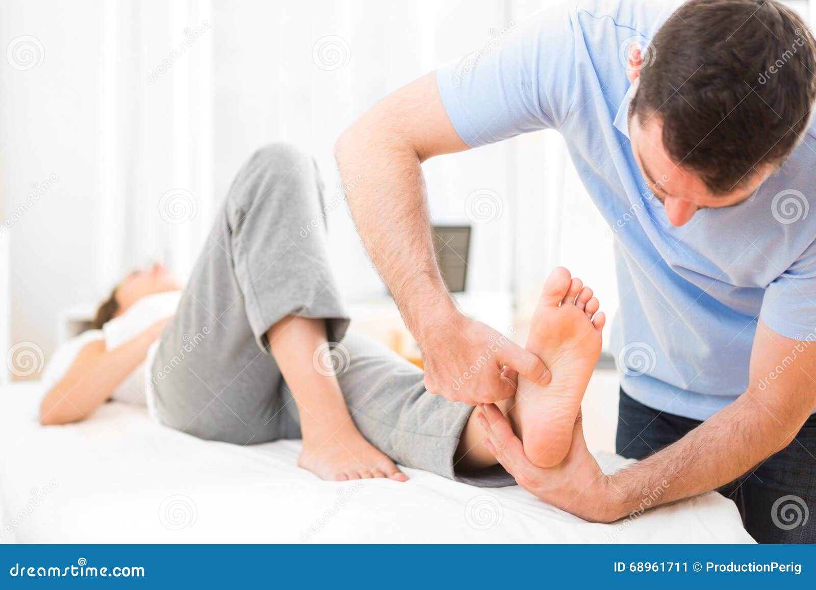 young attractive physiotherapist doing reflexology on a patient