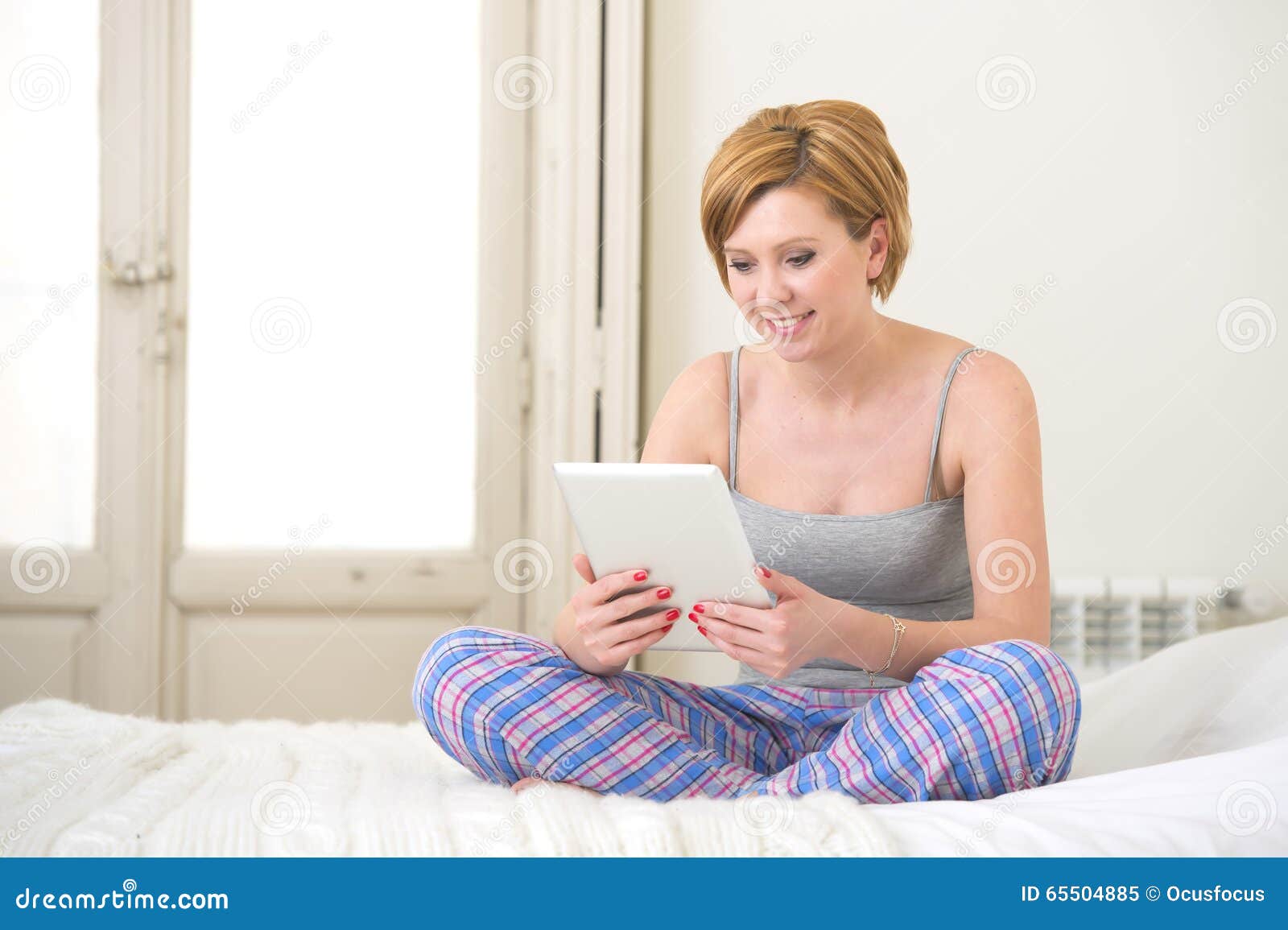 Young Attractive Red Hair Girl in Sleeping Tank Top and Pajamas Pants  Sitting on Bed at Home Using Internet Digital Tablet Pad Stock Image -  Image of digital, movie: 65504885