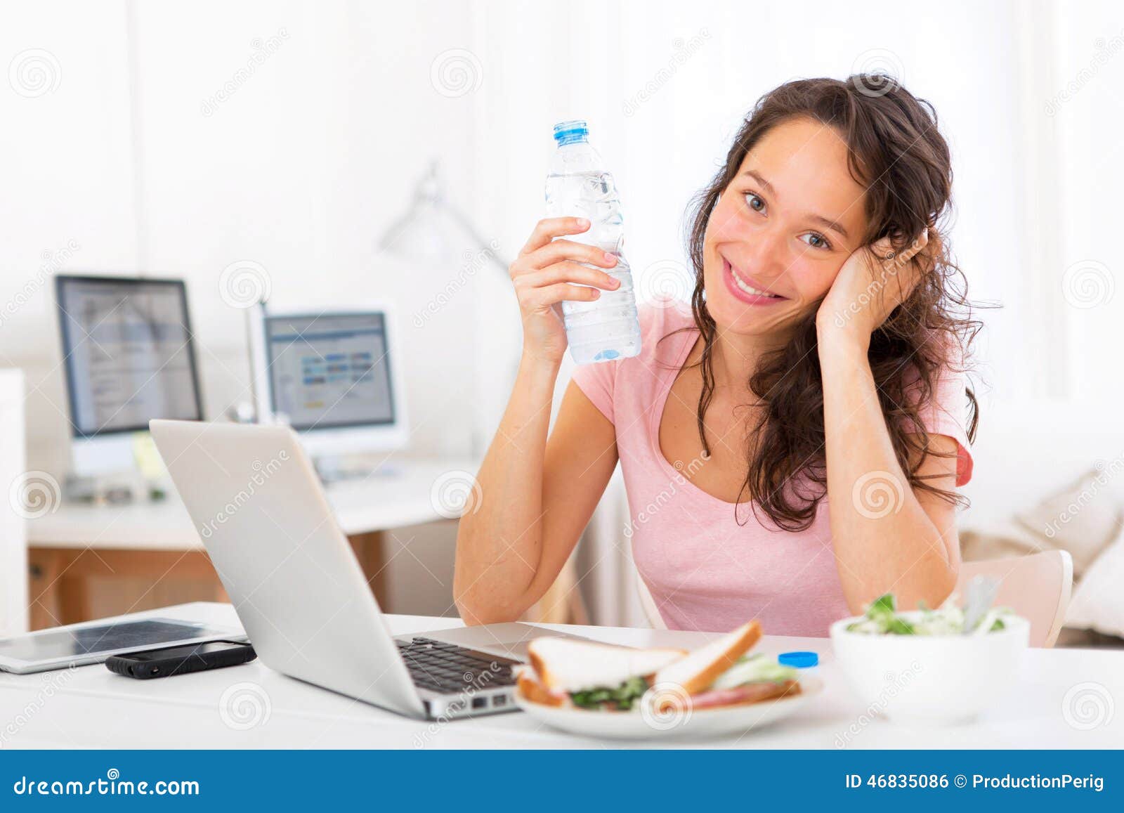 Young Attractive Student Drinking Water while Working Stock Photo
