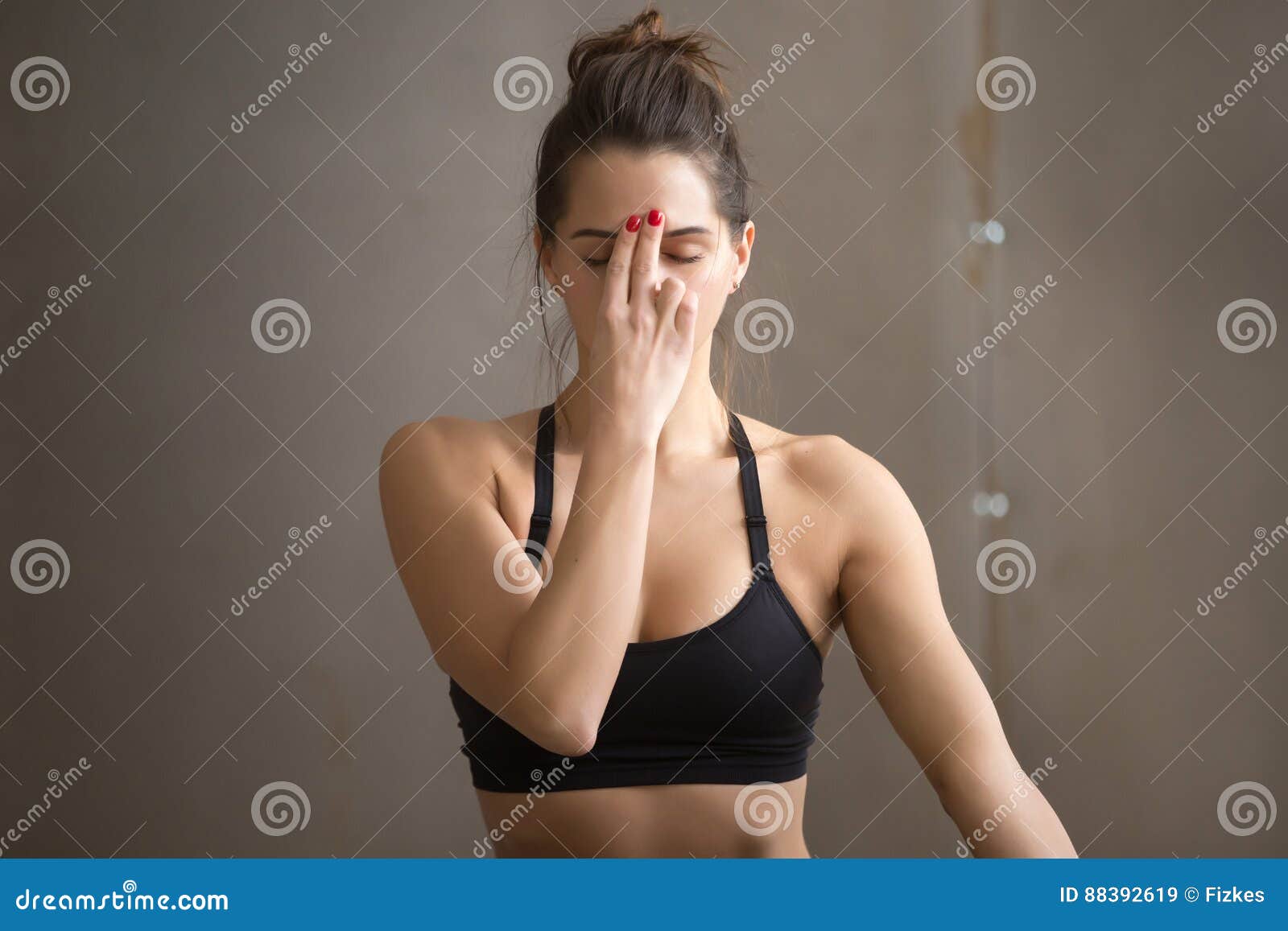 young attractive woman making alternate nostril breathing, grey