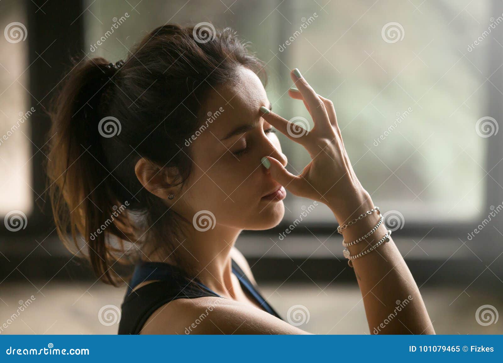 young attractive woman in alternate nostril breathing, studio ba