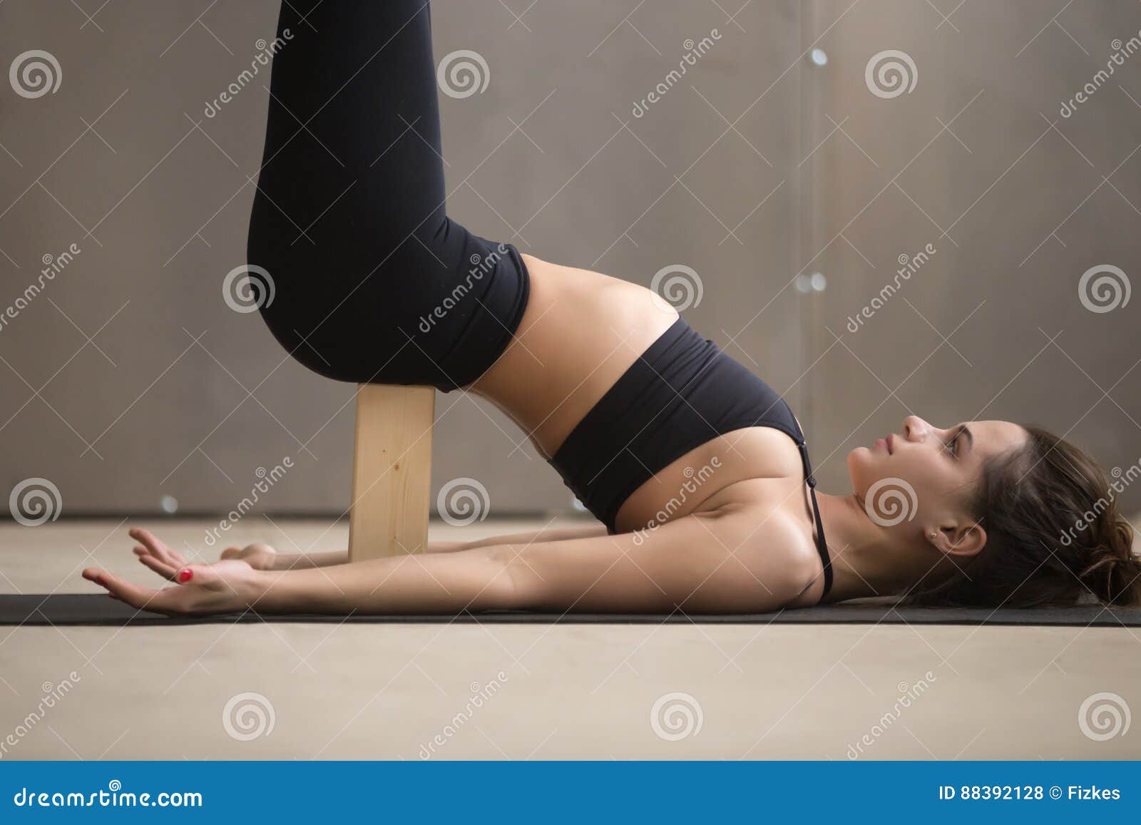 young attractive woman in viparita karani pose with block, close