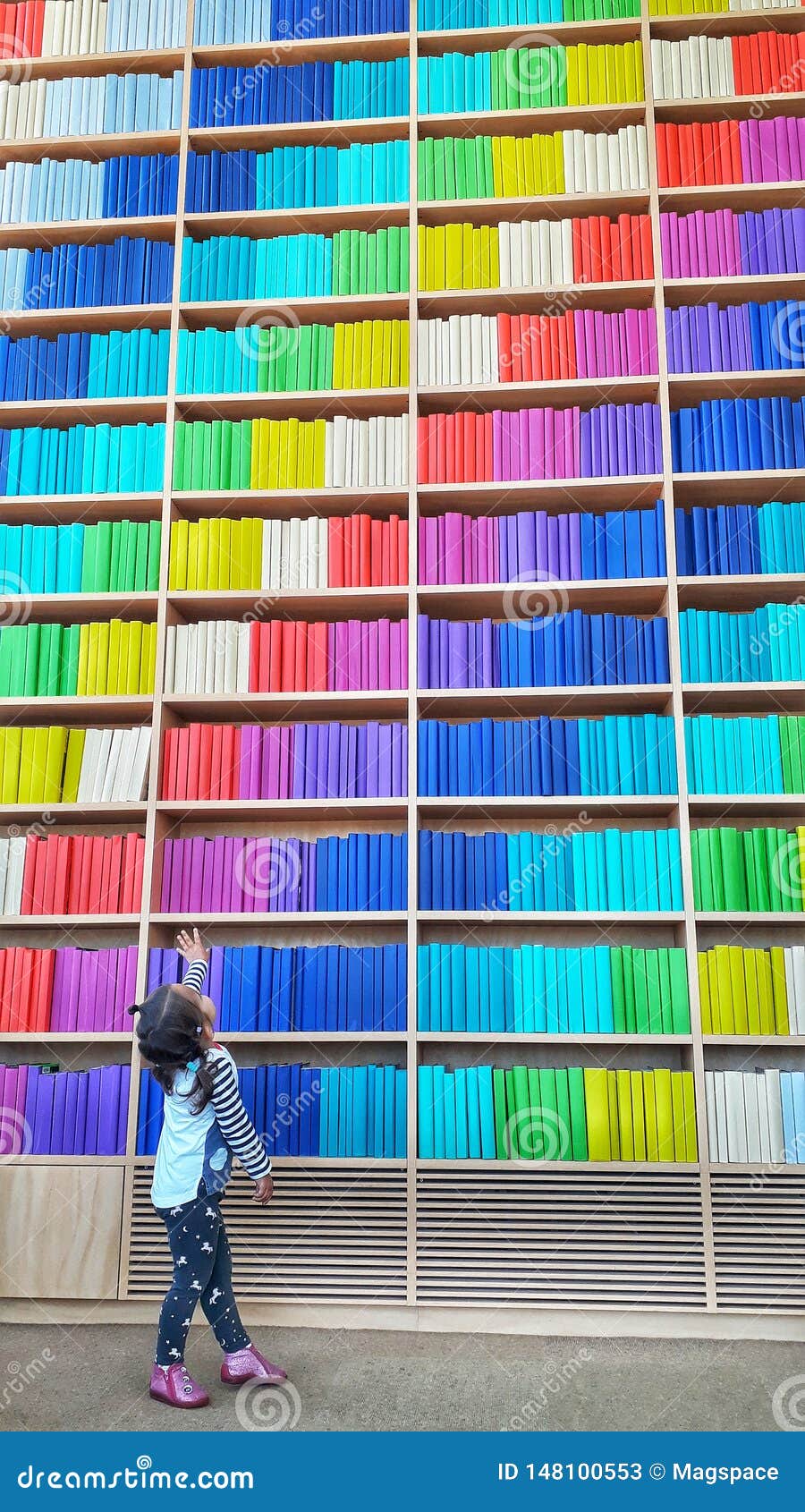 A Young Baby Girl In The Library Standing Near An Endless