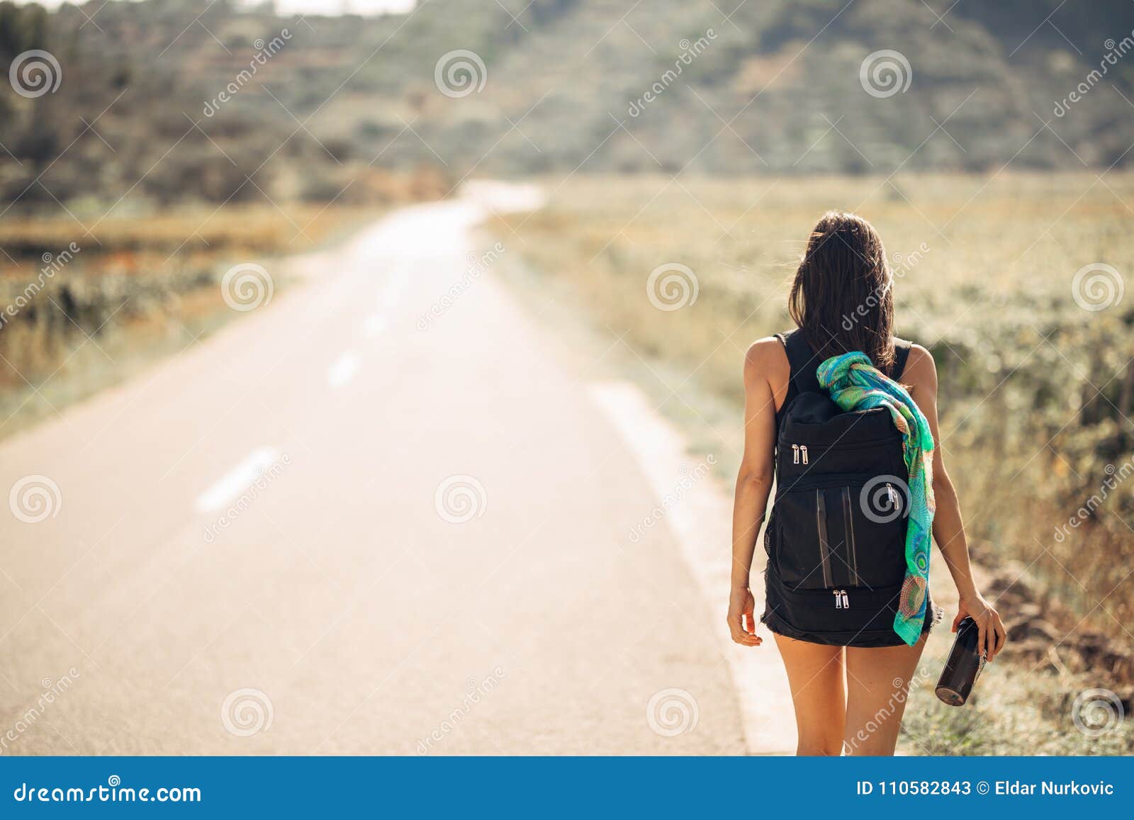 young backpacking adventurous woman hitchhiking on the road.traveling backpacks volume,packing essentials.travel lifestyle