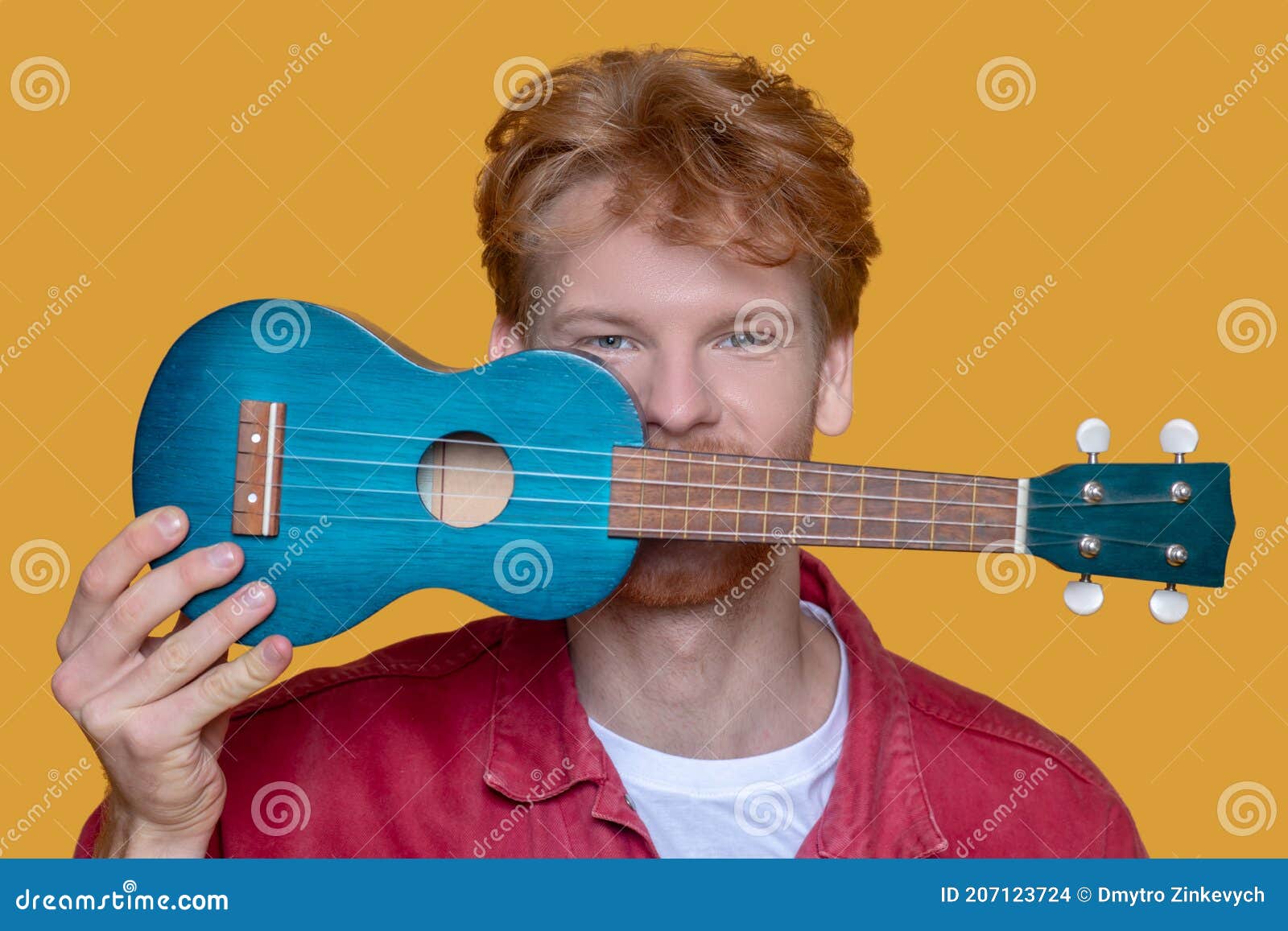 Young Bearded Goodlooking Man in Red Jacket with Ukulele Having Fun