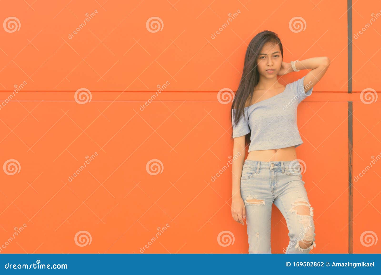 Young Beautiful Asian Teenage Girl Against Orange Wall Stoc