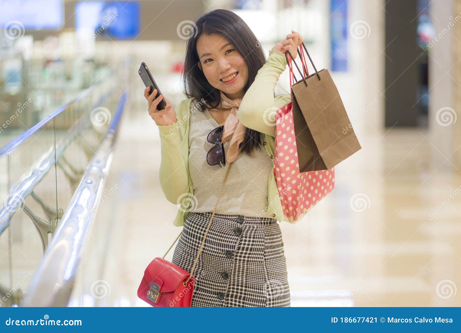 lifestyle indoors portrait of young happy and beautiful Asian Korean woman  shopping and using mobile phone at luxury bag shop walking around the store  Stock Photo - Alamy