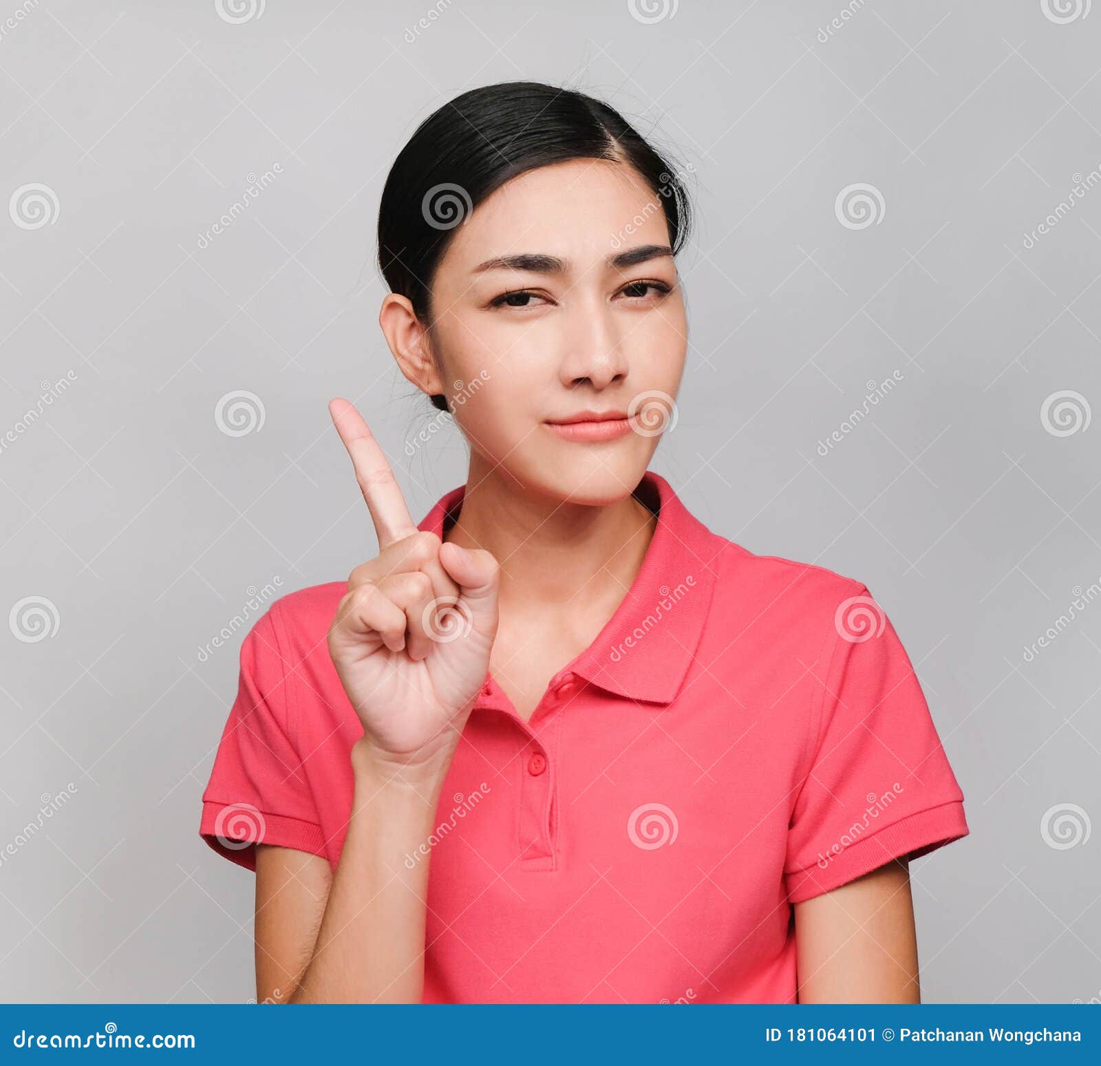 young beautiful asian woman wore pink t shirt, showed pointing and wondering expression , on gray background
