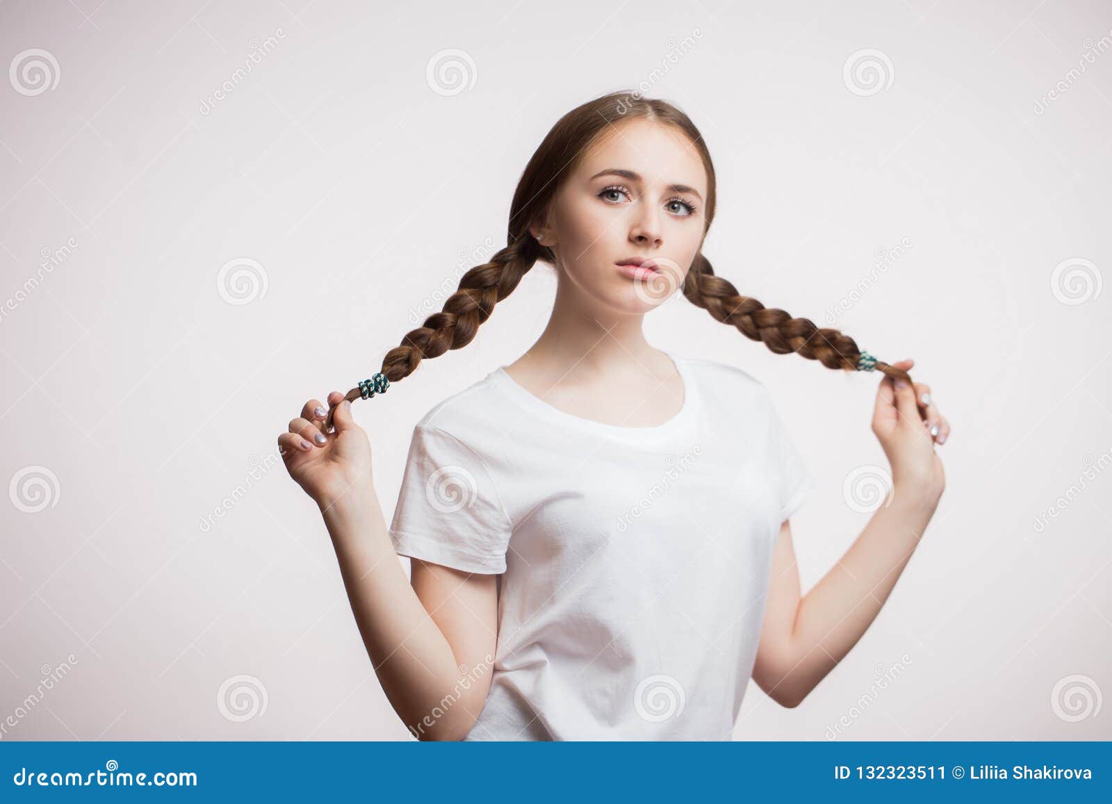 Young Beautiful Attractive Girl with Beauty Hair Holding for Long Braids on  a White Background. Student or Teen Stock Image - Image of emotions,  female: 132323511