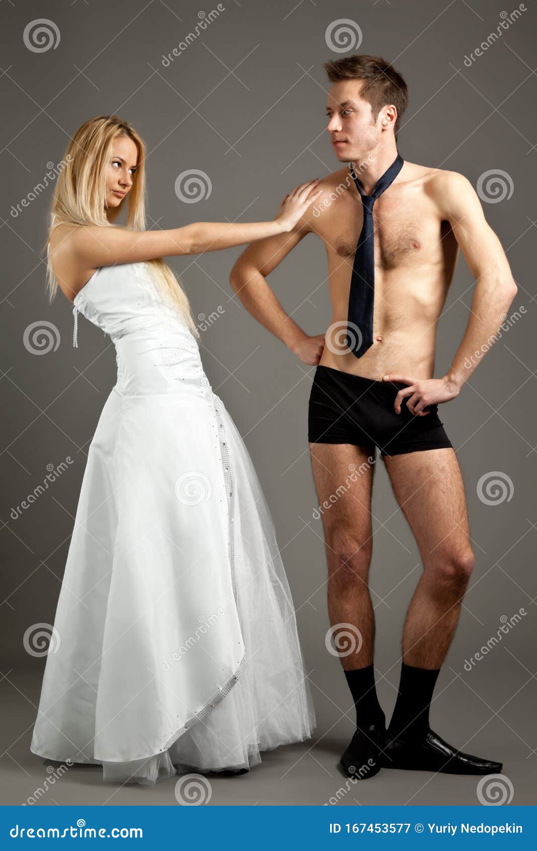 Young Woman in Wedding Dress Standing and Touching Man in Underwear Stock Image