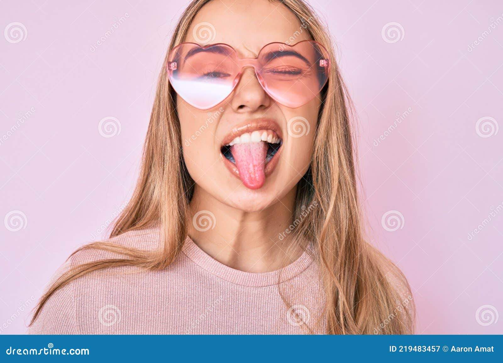 Young Beautiful Blonde Woman Wearing Heart Shaped Sunglasses Sticking Tongue Out Happy With 