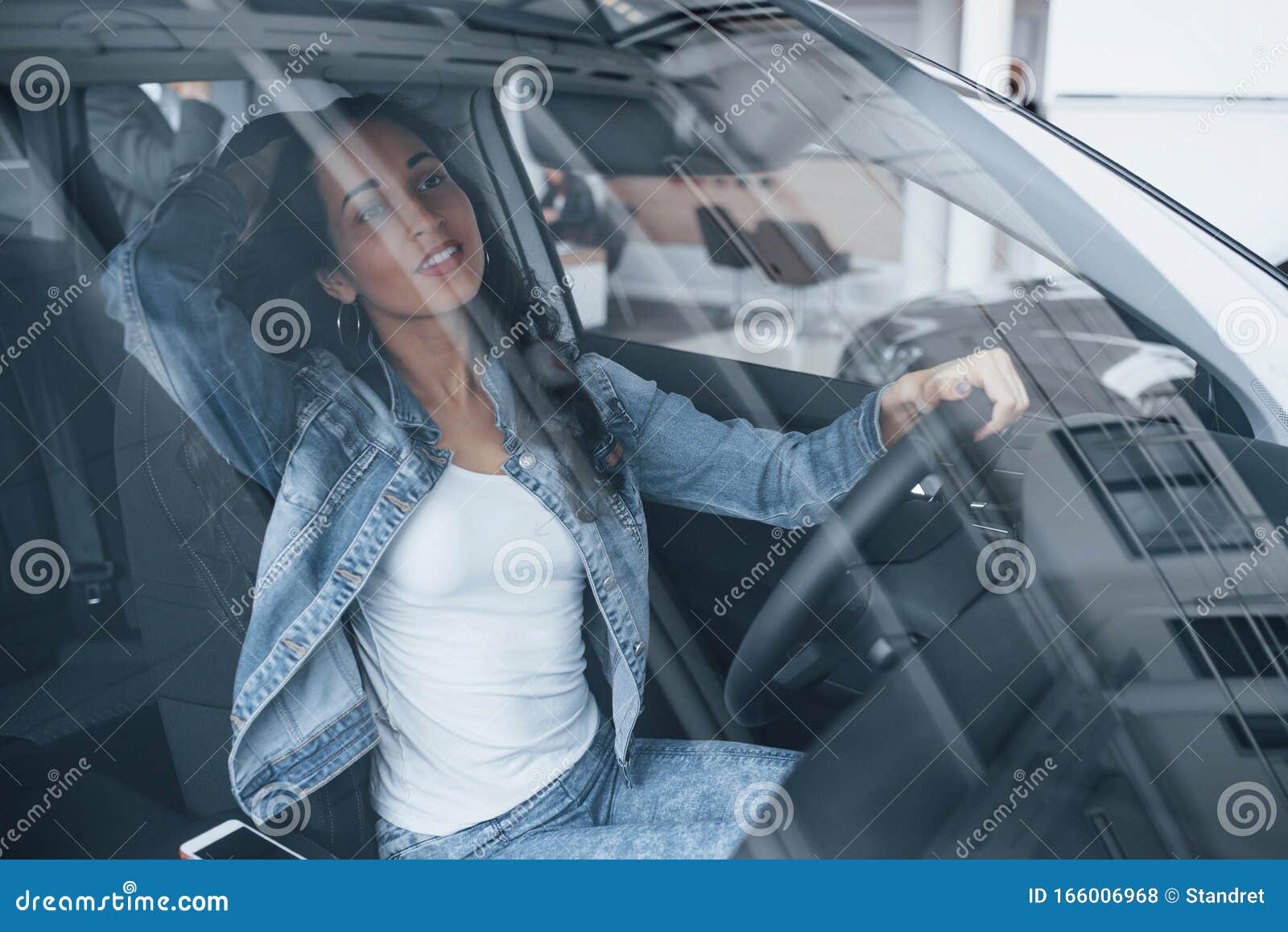 young and beautiful. cute girl with black hair trying her brand new expensive car in the automobile salon