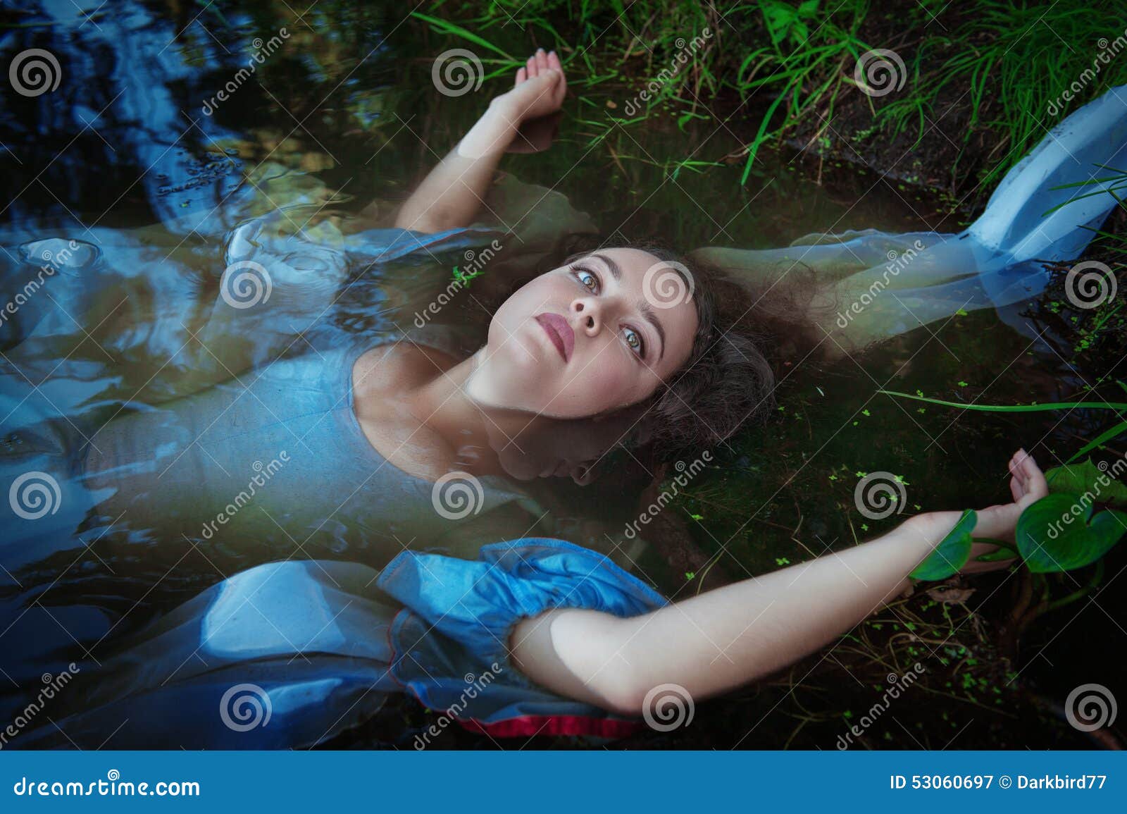 young beautiful drowned woman in blue dress lying in the water