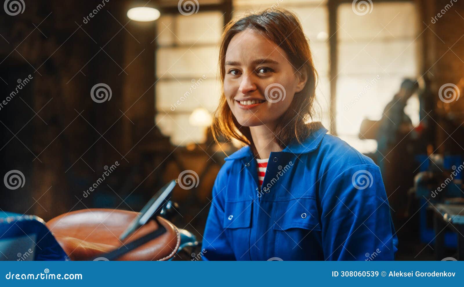 young beautiful empowering woman gently smiles at the camera. authentic fabricator wearing work cl